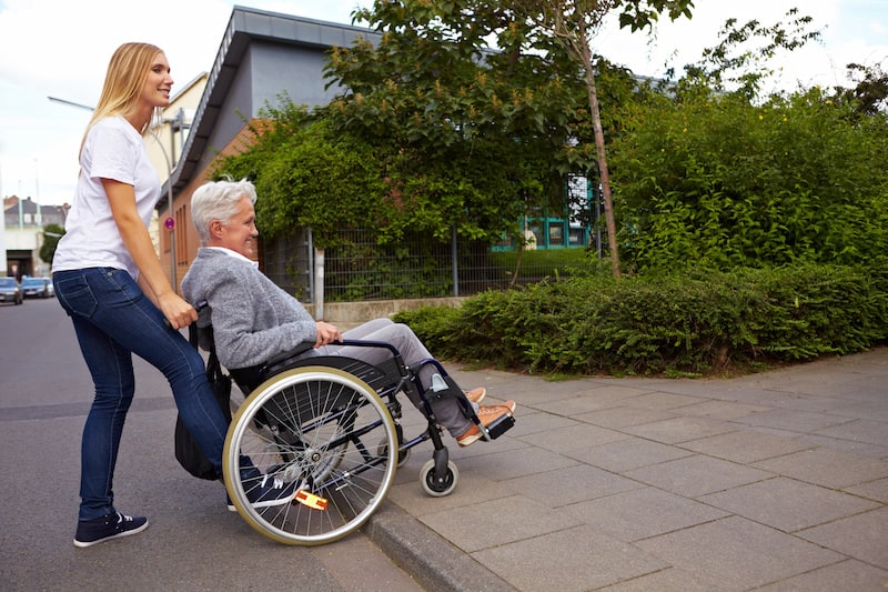 Andere-Teilnehmer-Strassenverkehr-Frau-hilf-Mann-im-Rollstuhl-ueber-Strasse.jpeg
